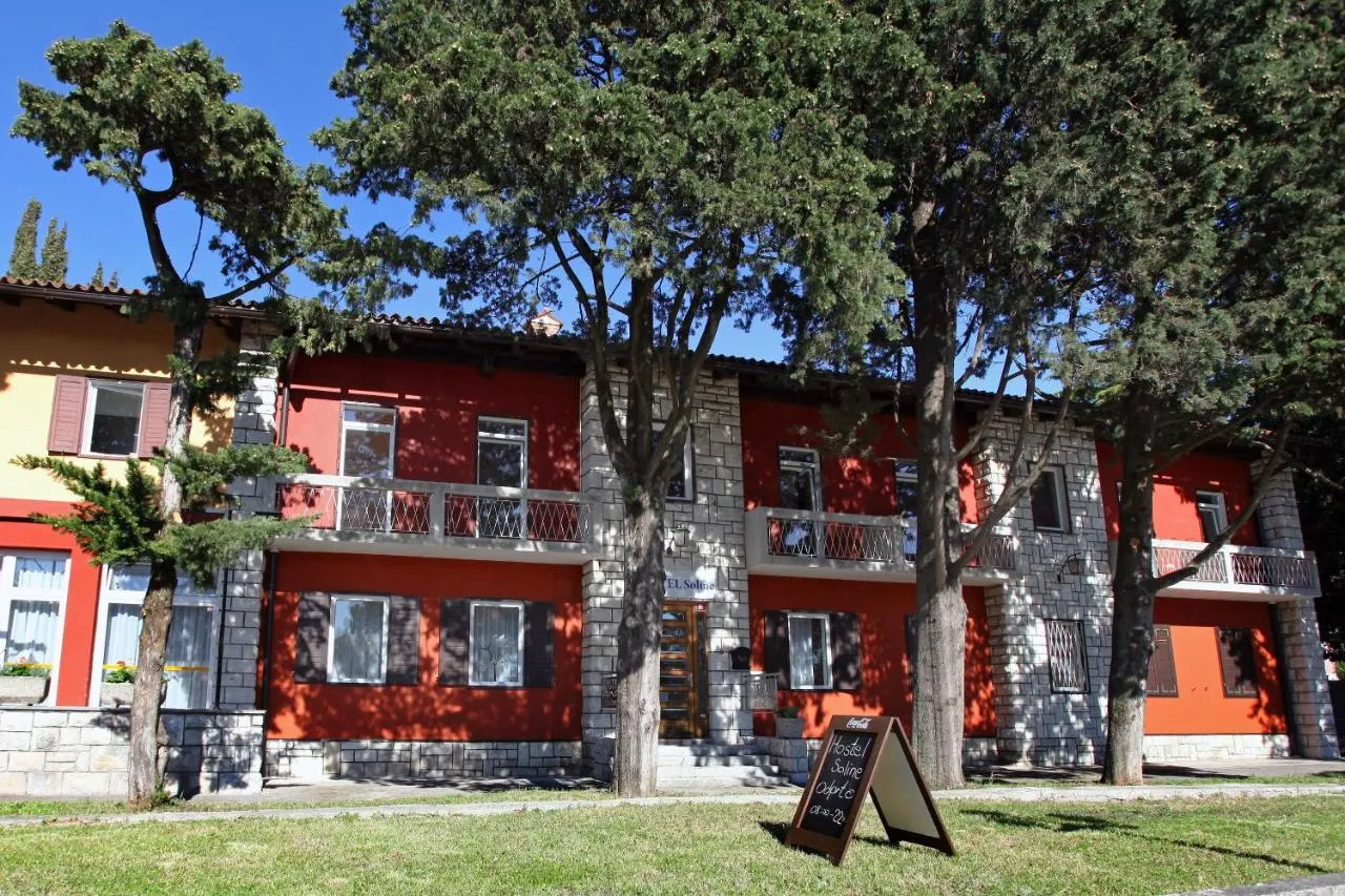 Pročelje hostla z rdečimi in kamnitimi stenami ob drevoredu